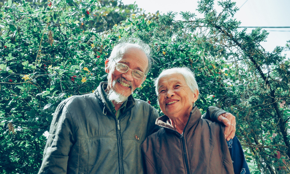 Smiling man and woman standing in front of trees
