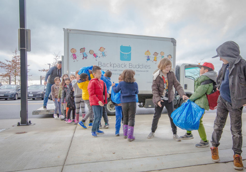 Kids lining up to help unload a Backpack Buddies van.