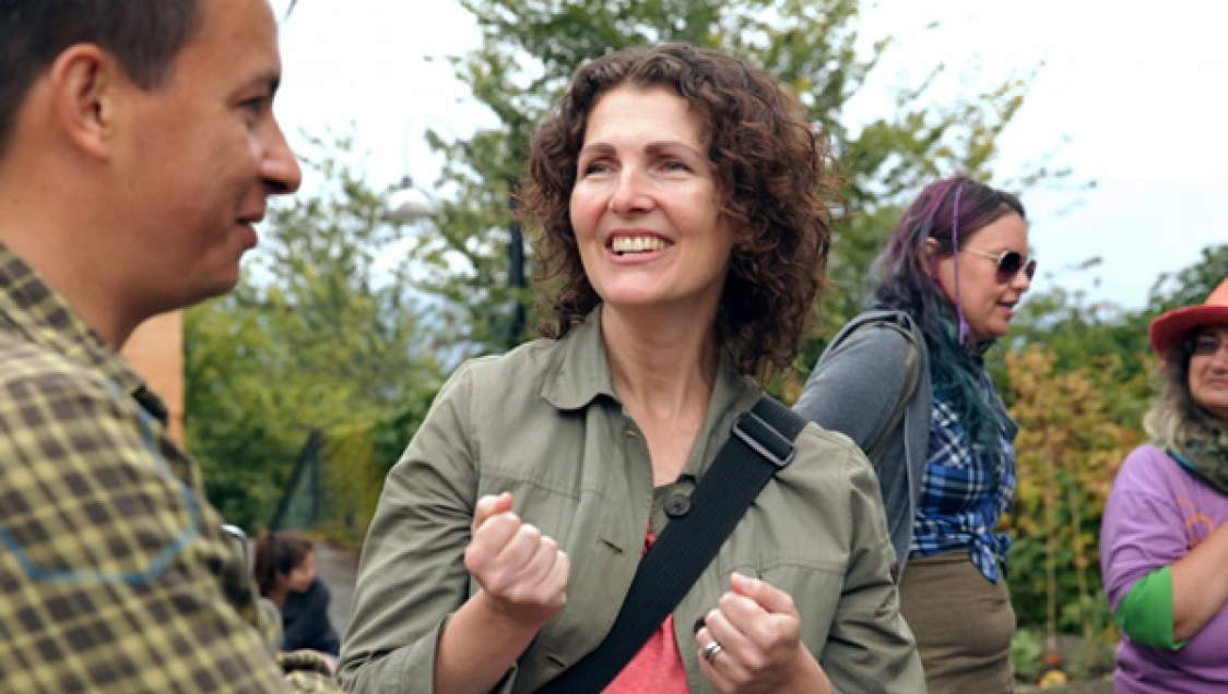 Two adults talking outdoors, with two other adults in the background.