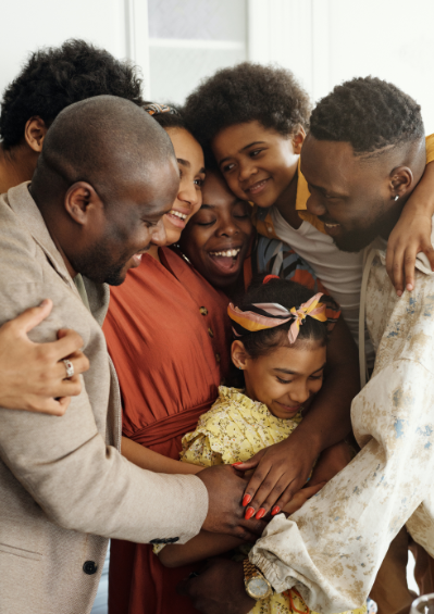 Black extended family all hugging and wearing warm fall colours.