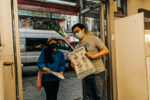 Carmut from hua foundation passes out posters to a business owner in Chinatown.