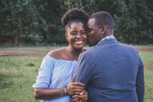 Black couple wearing blue, smiling and being affectionate with each other.