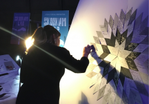 Person piecing together notes onto a canvas to create a Starblanket of stories.