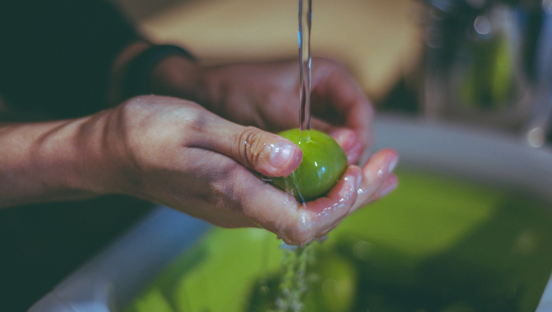 Person washing a green tomato