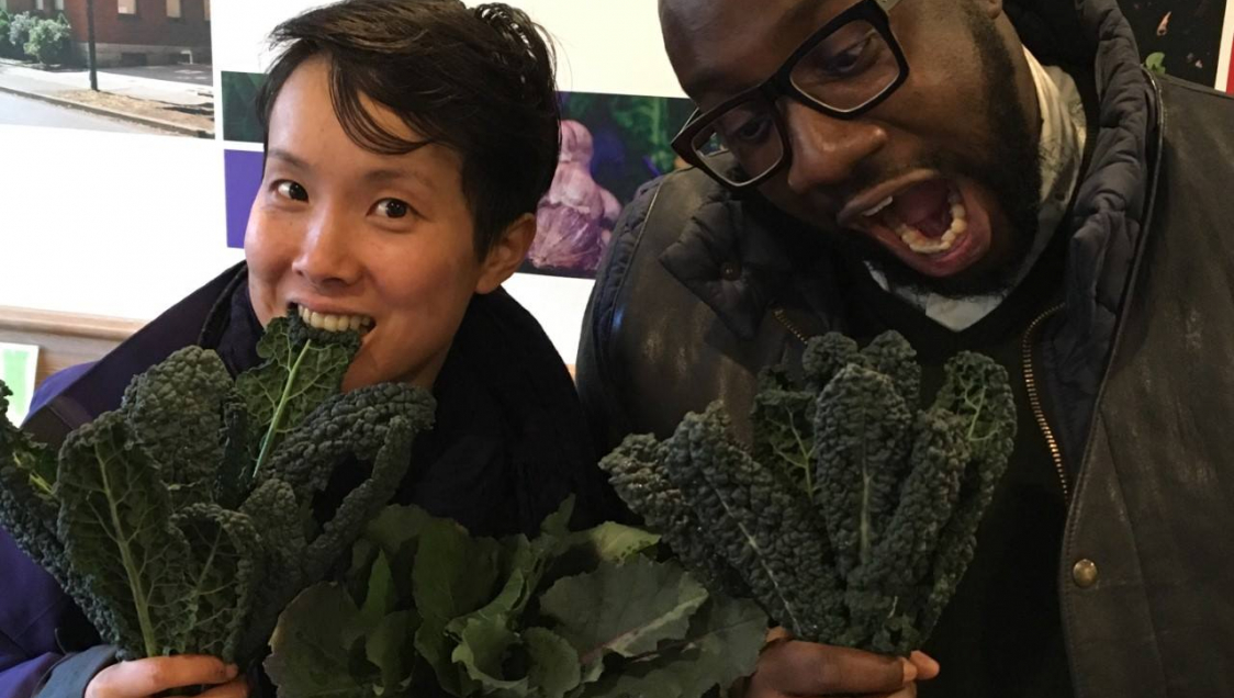 Two people holding kale and playfully going in for a bite