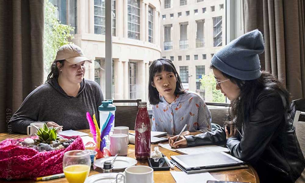 Three young women of colour sitting around a table in serious discussion