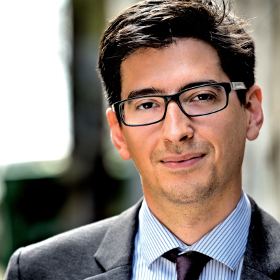 Headshot of Andrew Kohlgrueber, a smiling man with short dark hair and glasses, wearing a suit and tie