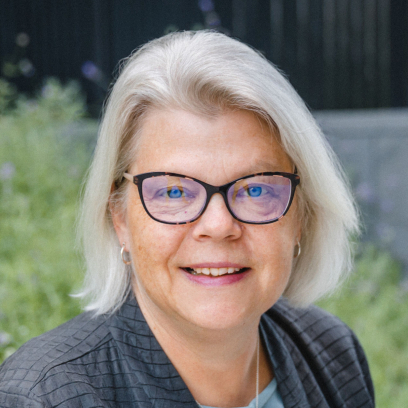 Headshot of Elisabeth Geller, a smiling woman with white hair, wearing glasses