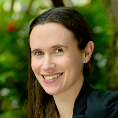 Headshot of Julie Howald, a smiling woman with long dark brown hair and light eyes wearing stud earrings and a dark blazer