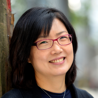 Headshot of Kelly Kim, a smiling woman with dark hair and red rimmed glasses wearing a dark blouse