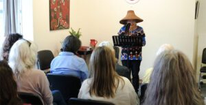 Myra Pierre reads poetry to an audience while holding an eagle feather