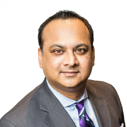 Headshot of Nav Maharaj. He has short dark hair and brown eyes, and is wearing a grey suit, light shirt, and purple, black and white patterned tie.
