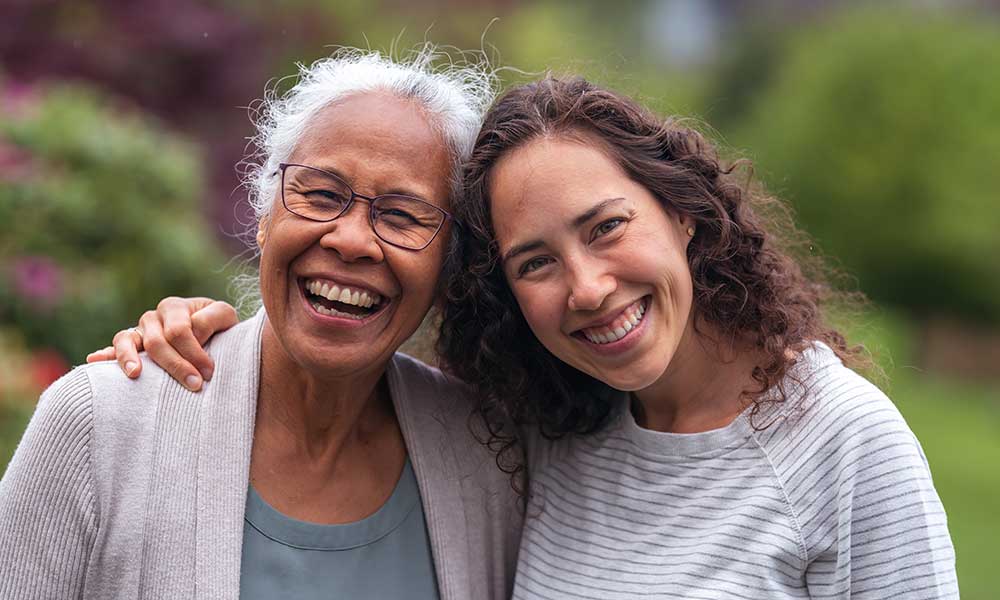 Older woman laughing with her younger daughter in a park