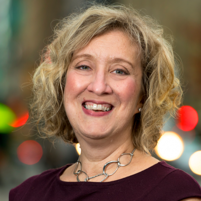 Headshot of Tina Logan, She has light eyes and wavy short blonde hair.