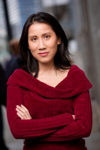 Portrait of a woman with long dark hair and eyes wearing a red sweater with arms crossed