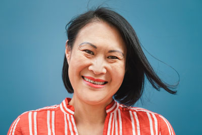 Asian woman with a bob and red striped button up against blue background