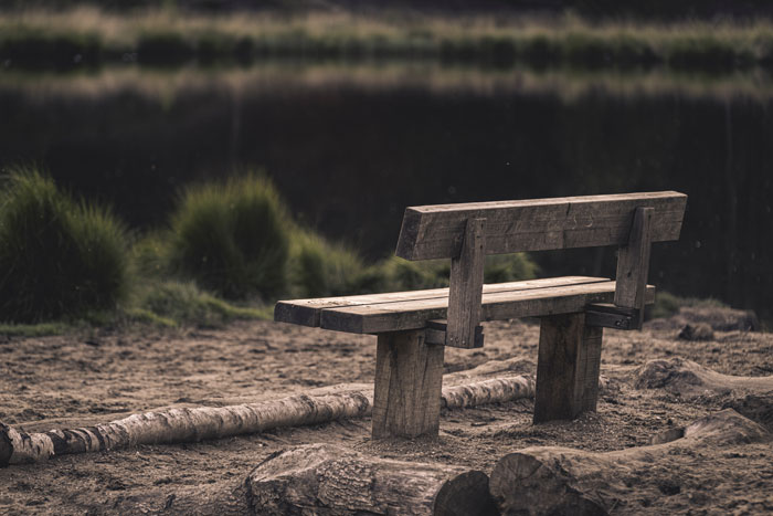 Empty bench looking out at a lake. Credit Atijs van Leur via Unsplash
