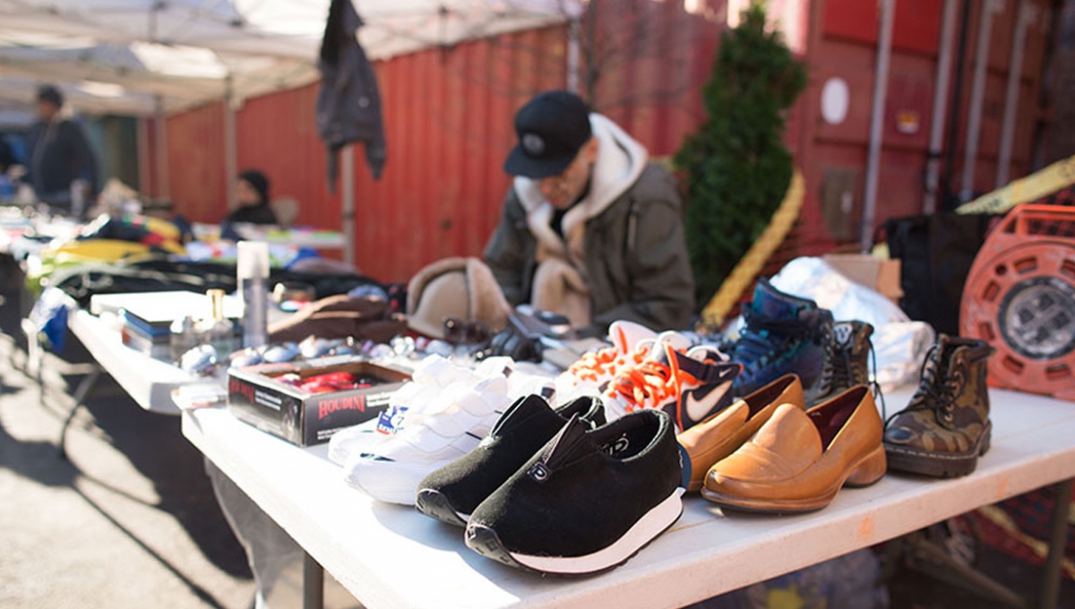 A collection of varous shoes grouped together on a sellers table at an open market