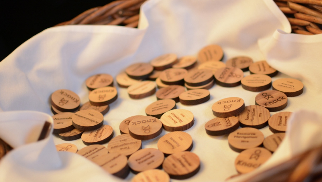 Little wooden disks in a cloth lined wicker basket, with the word "Knack" stamped on each