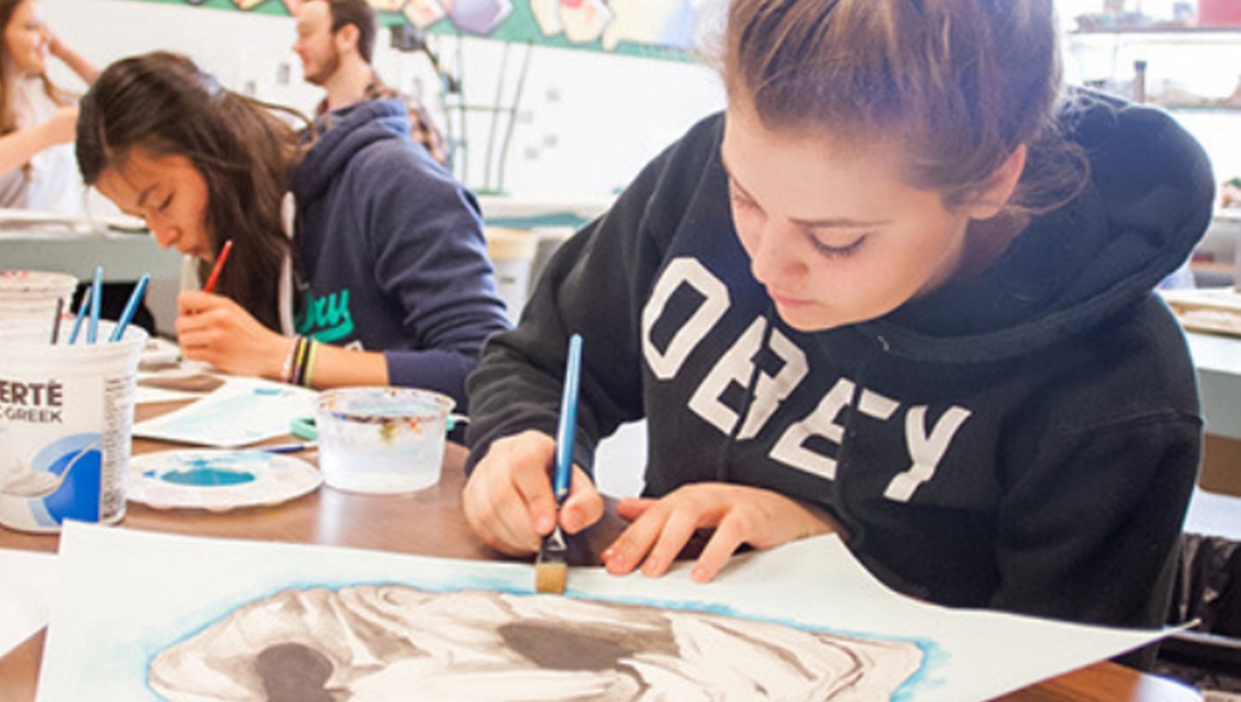 Two young women sitting at a table and painting 