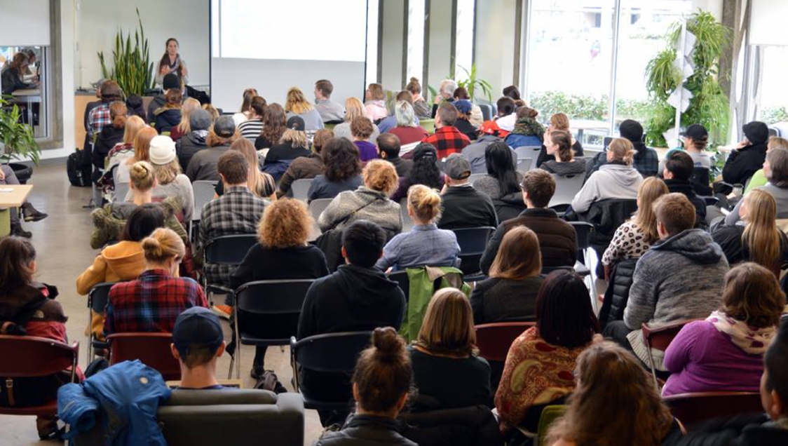 A woman speaking to a large and diverse group of people.