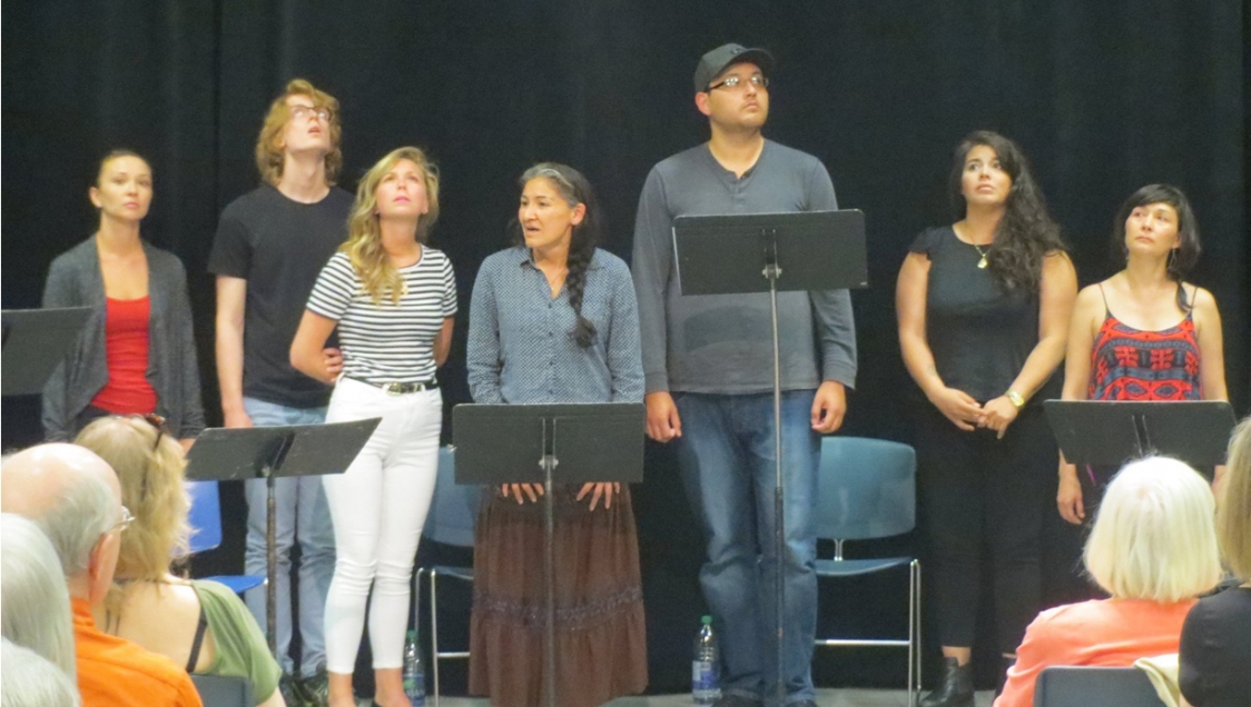 A diverse group of men and women standing in front of music stands.