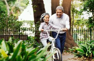 An older man helping a child learn how to bike