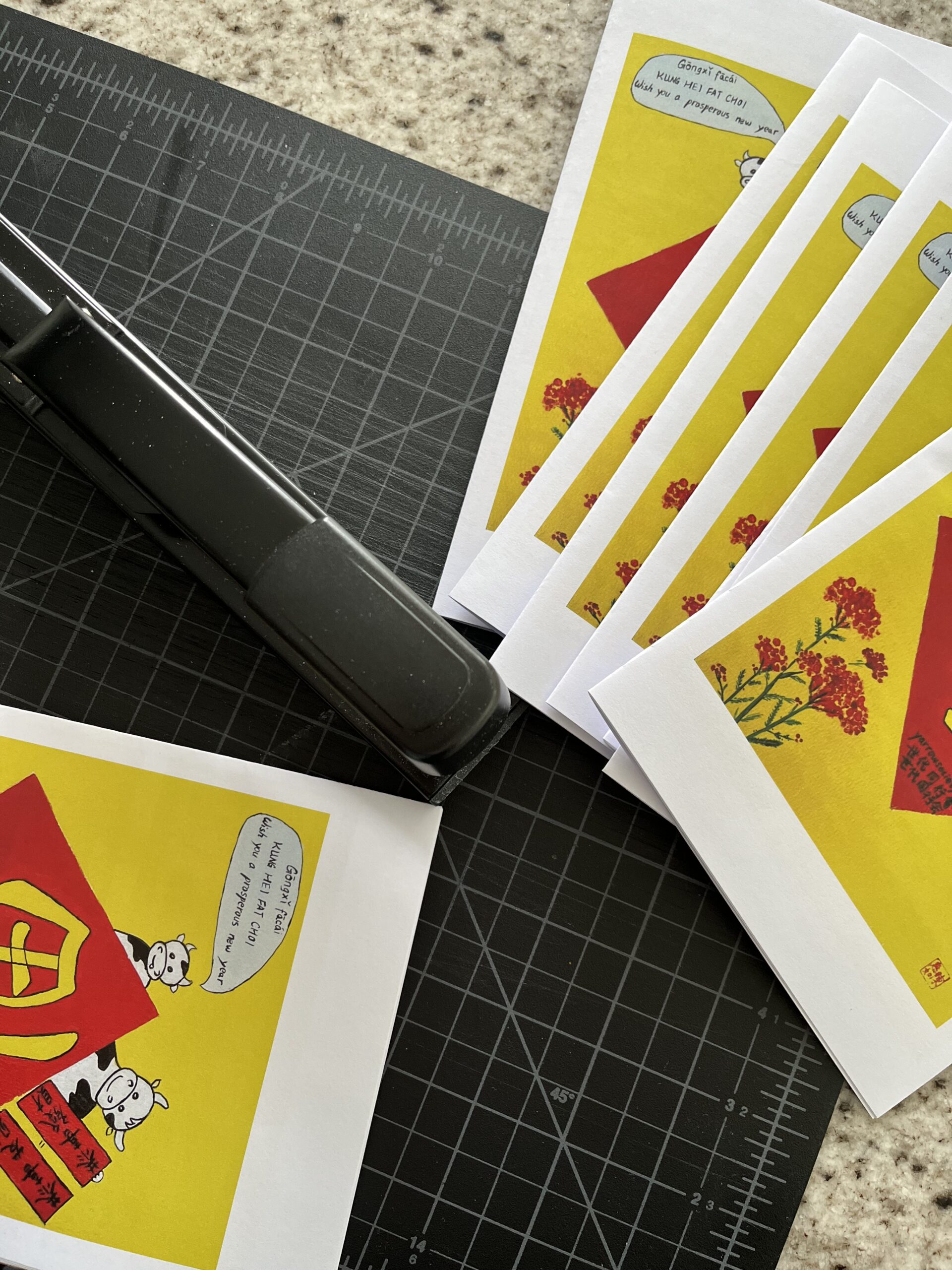 Copies of Sticky Rice's Lunar New Year zine spread out on a table ready to be cut to size.