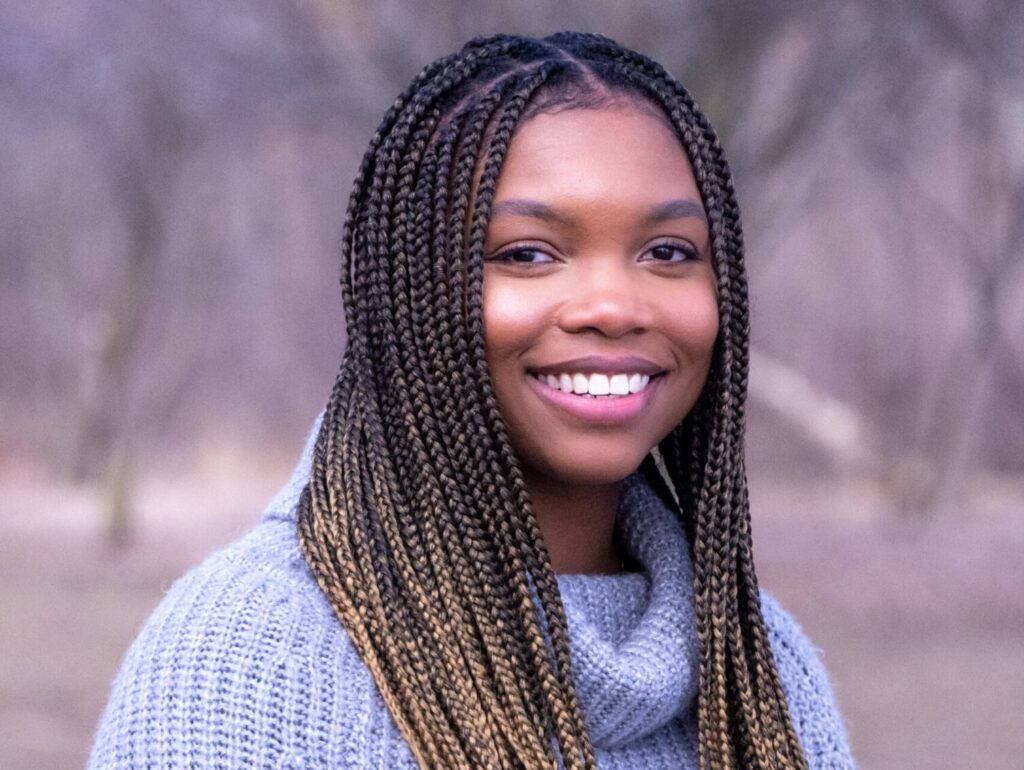 A person with long hair is pictured smiling at the camera.