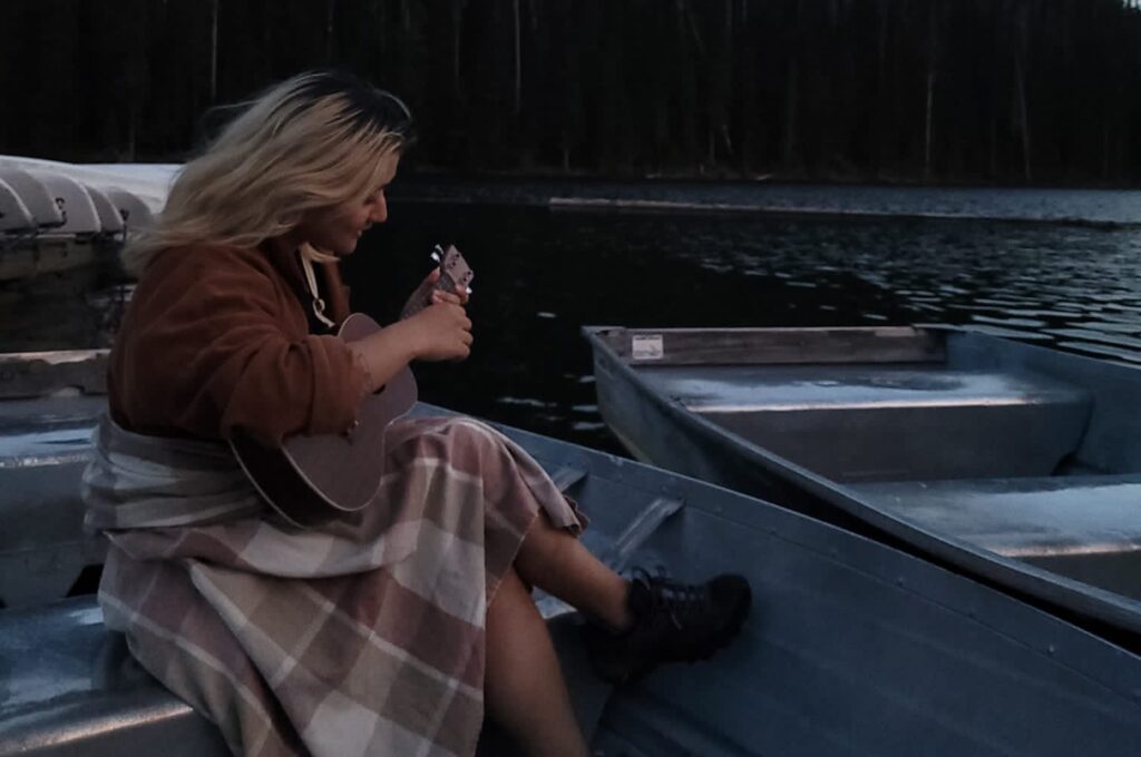 A person is pictured playing their ukulele on a boat.