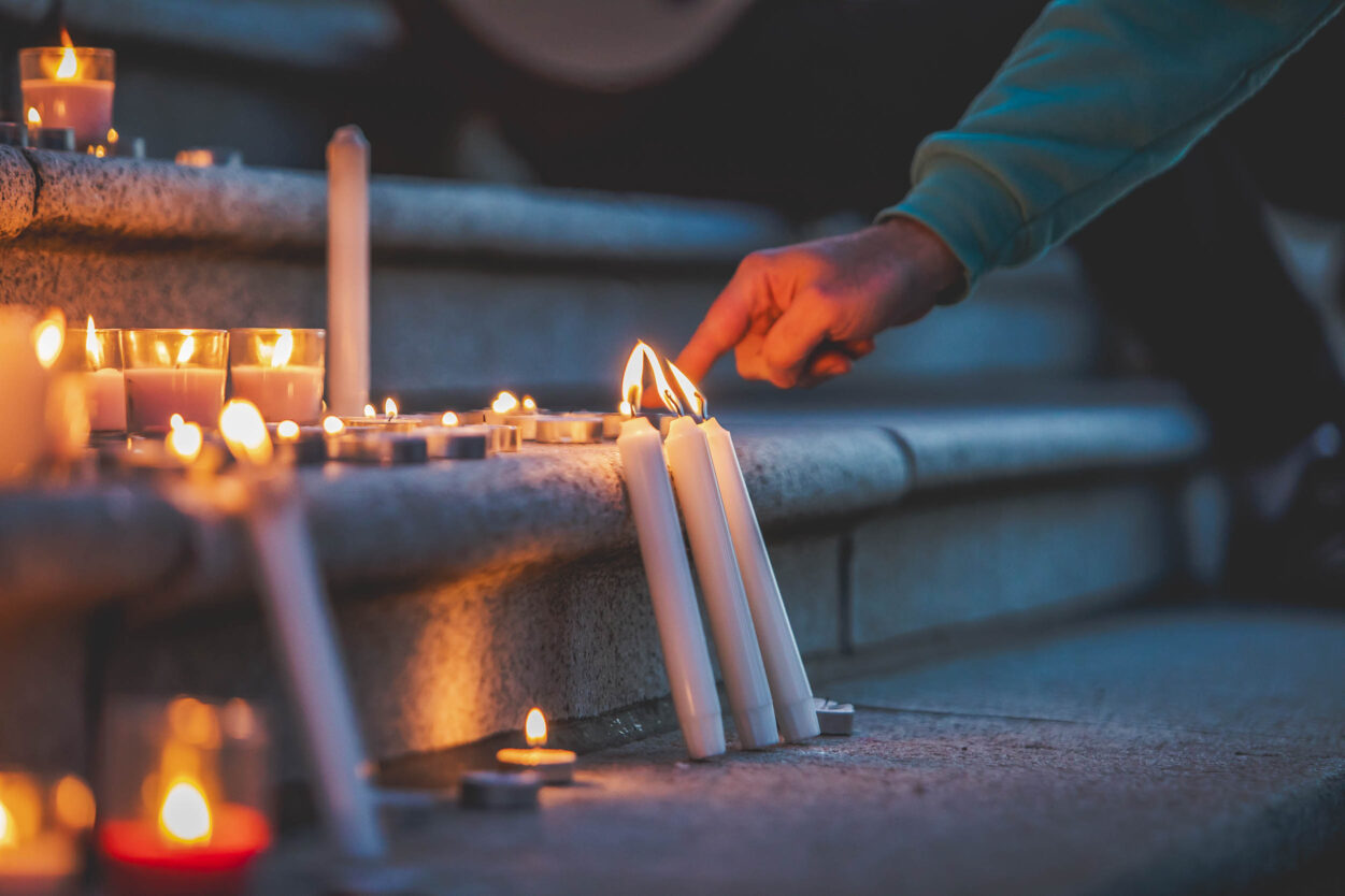 Lapu-Lapu-Victoria Close up of a hand fixing candles lined up across stairs at an outdoor vigil.