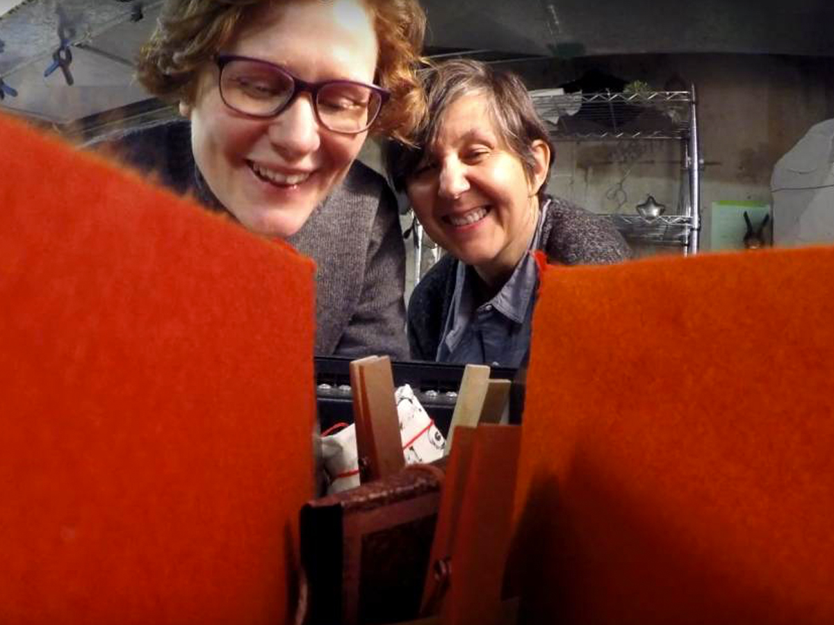 DTES-art-fall-2017 Two people smiling down at art supplies.