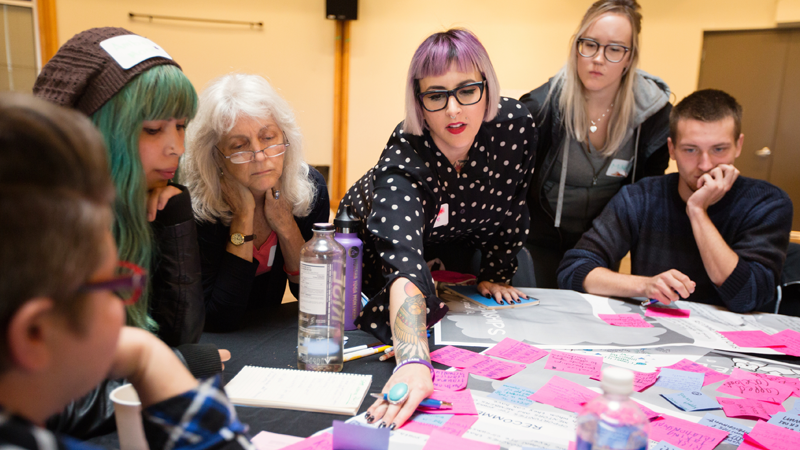 A diverse group of people sitting around a table and consulting notes