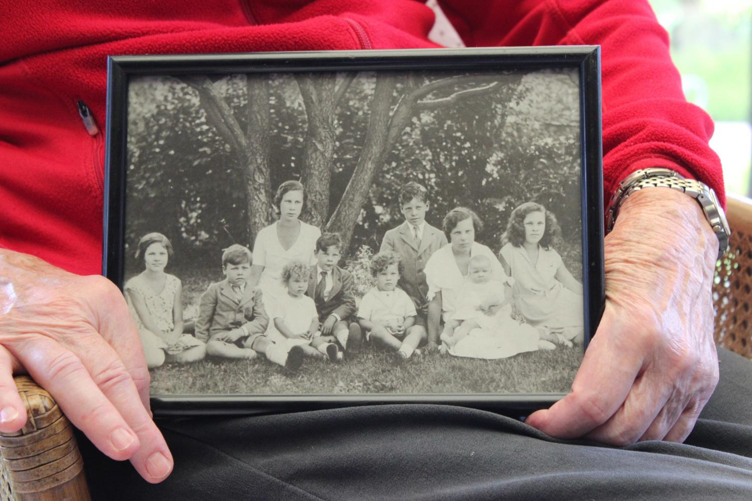 A pair of aged hands holding a framed black and white picture of young women and children