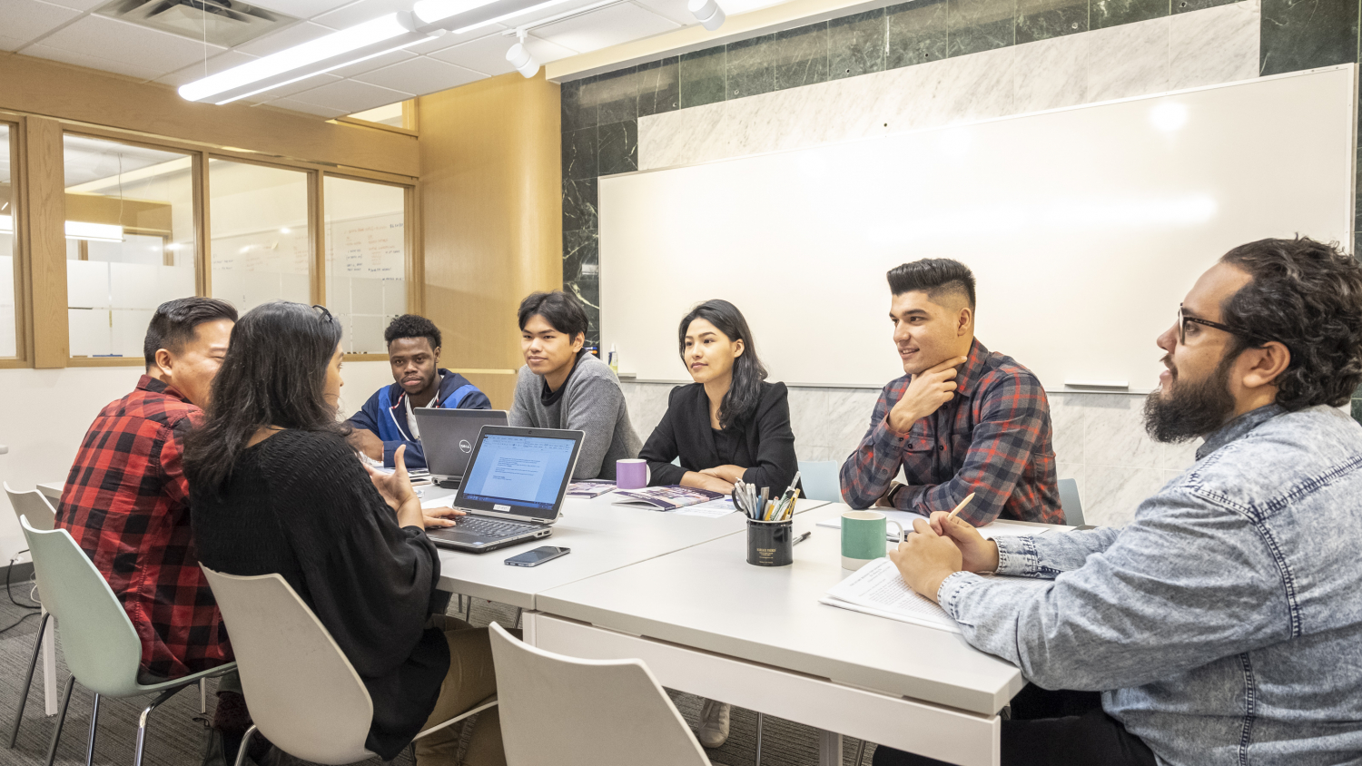 A diverse group of young people sitting around a long table, having a conversation