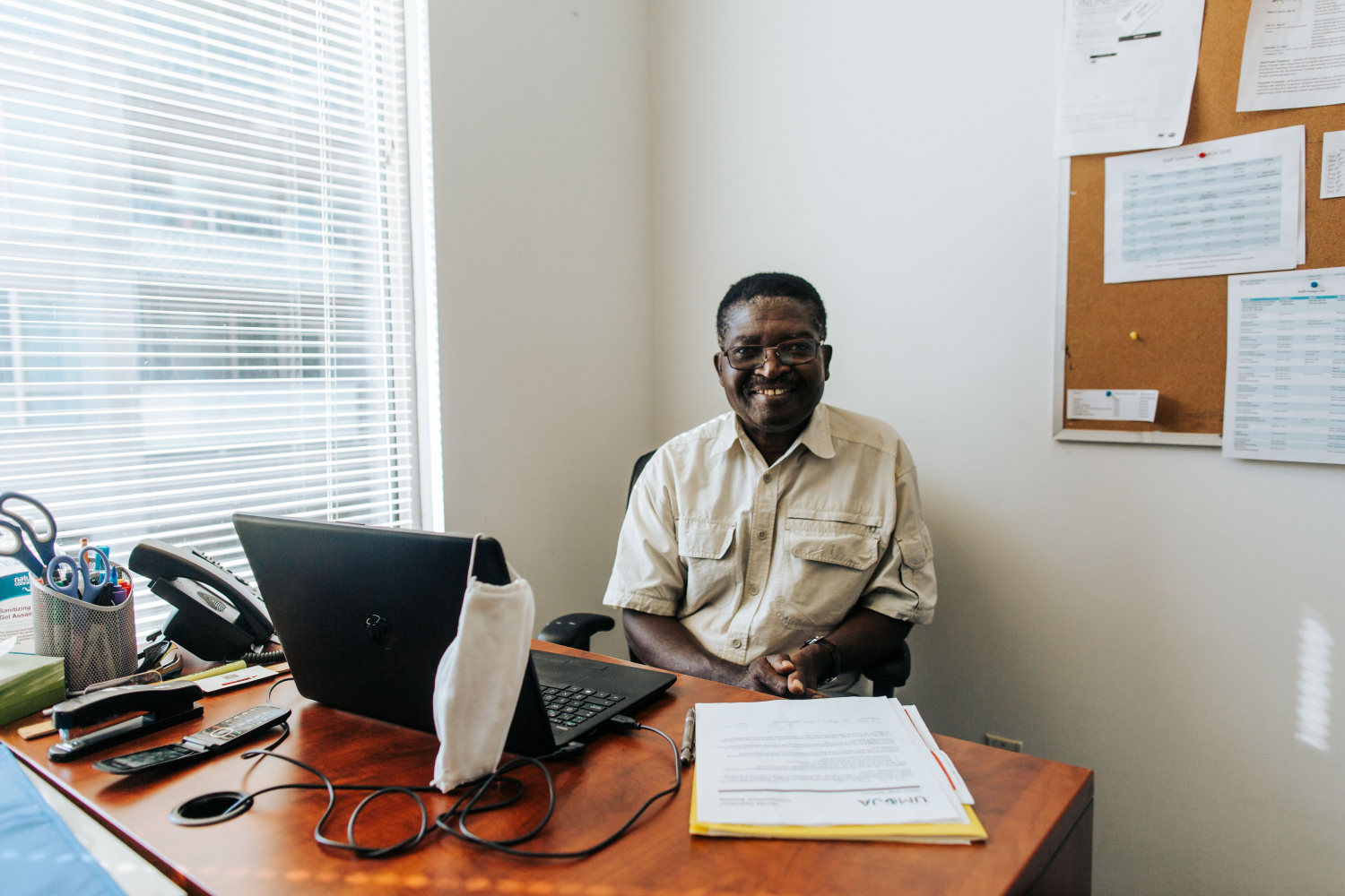 A smiling black man sitting at his desk with a laptop