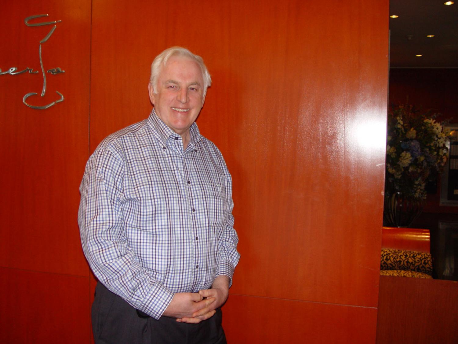 Peter Webster, a smiling man leaning against a wooden panel