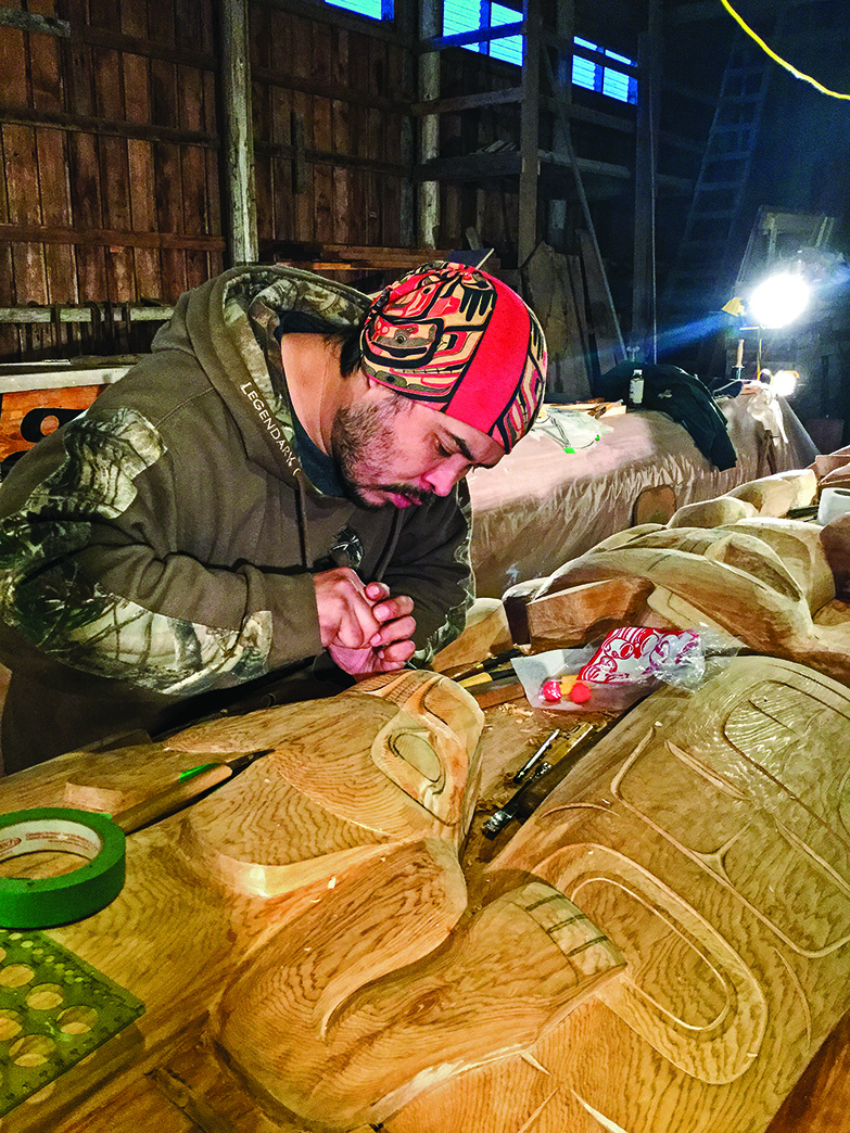 An indigenous artist in his workshop, working on wood-carving a totem