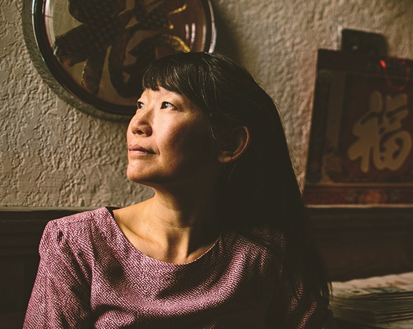 Side profile of an asian woman with long hair looking pensive